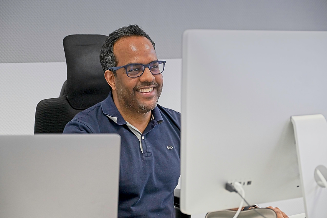 Ein lächelnder Mitarbeiter von uns arbeitet an einem Computer in unserem modernen Büro.